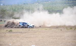 a rally car speeding through a dusty track in the WRC safari rally 2024 kenya.