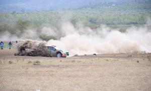 a Škoda Fabia R5 speeding through a dusty track in the 2024 WRC Safari Rally Kenya