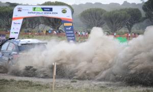 a rally car speeding through a dusty track